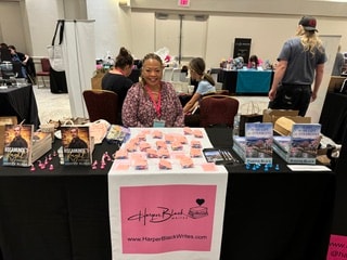 Harper Black at her convention booth with books and merchandise